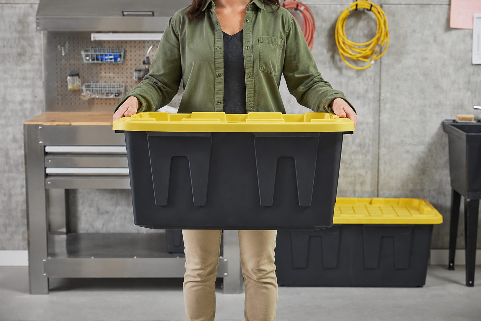 Person comfortably carrying a black moving tote with yellow lid